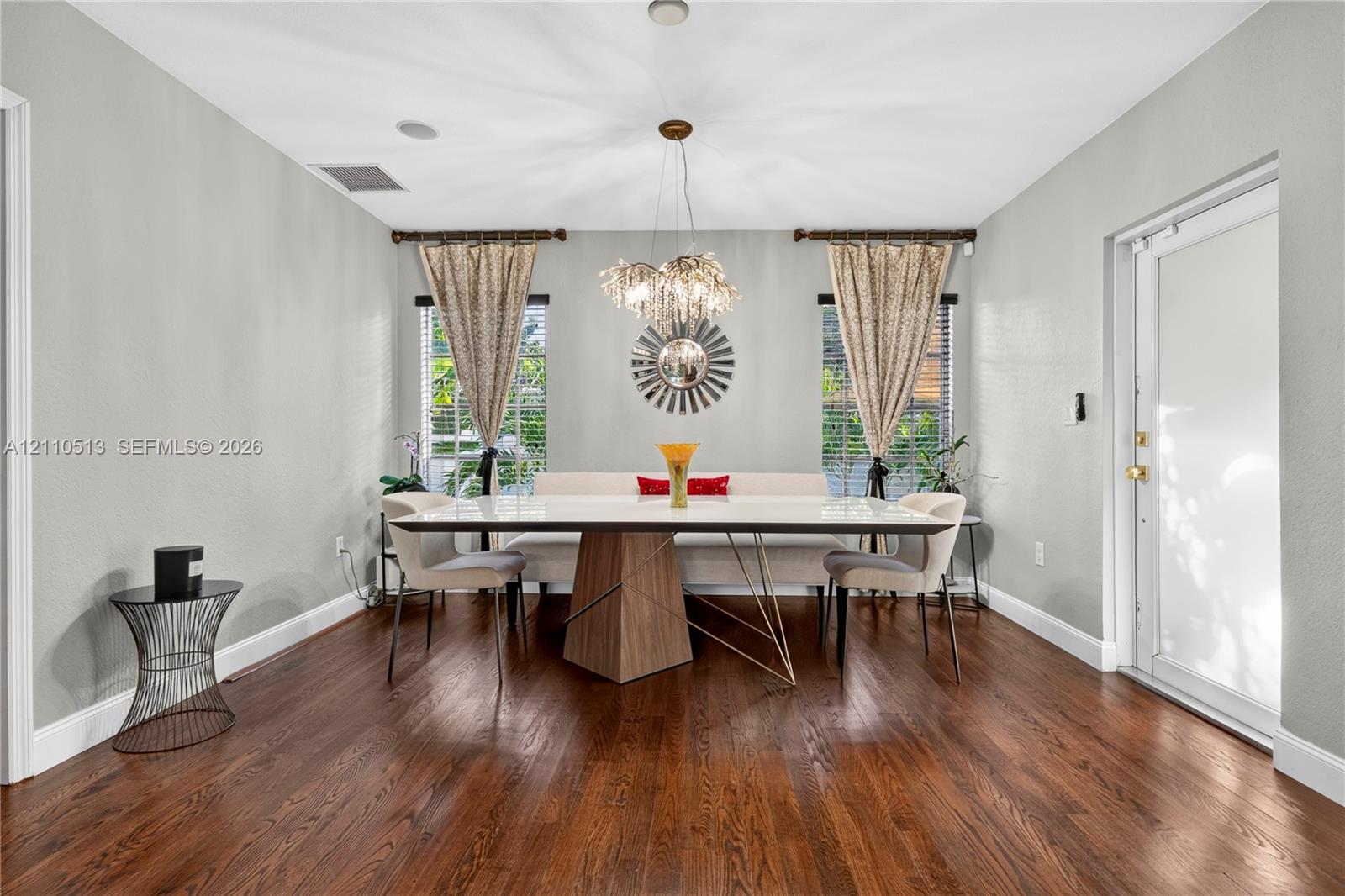 Wood-finish flooring, recessed ceiling lighting, a multi-tiered crystal chandelier, and dual windows