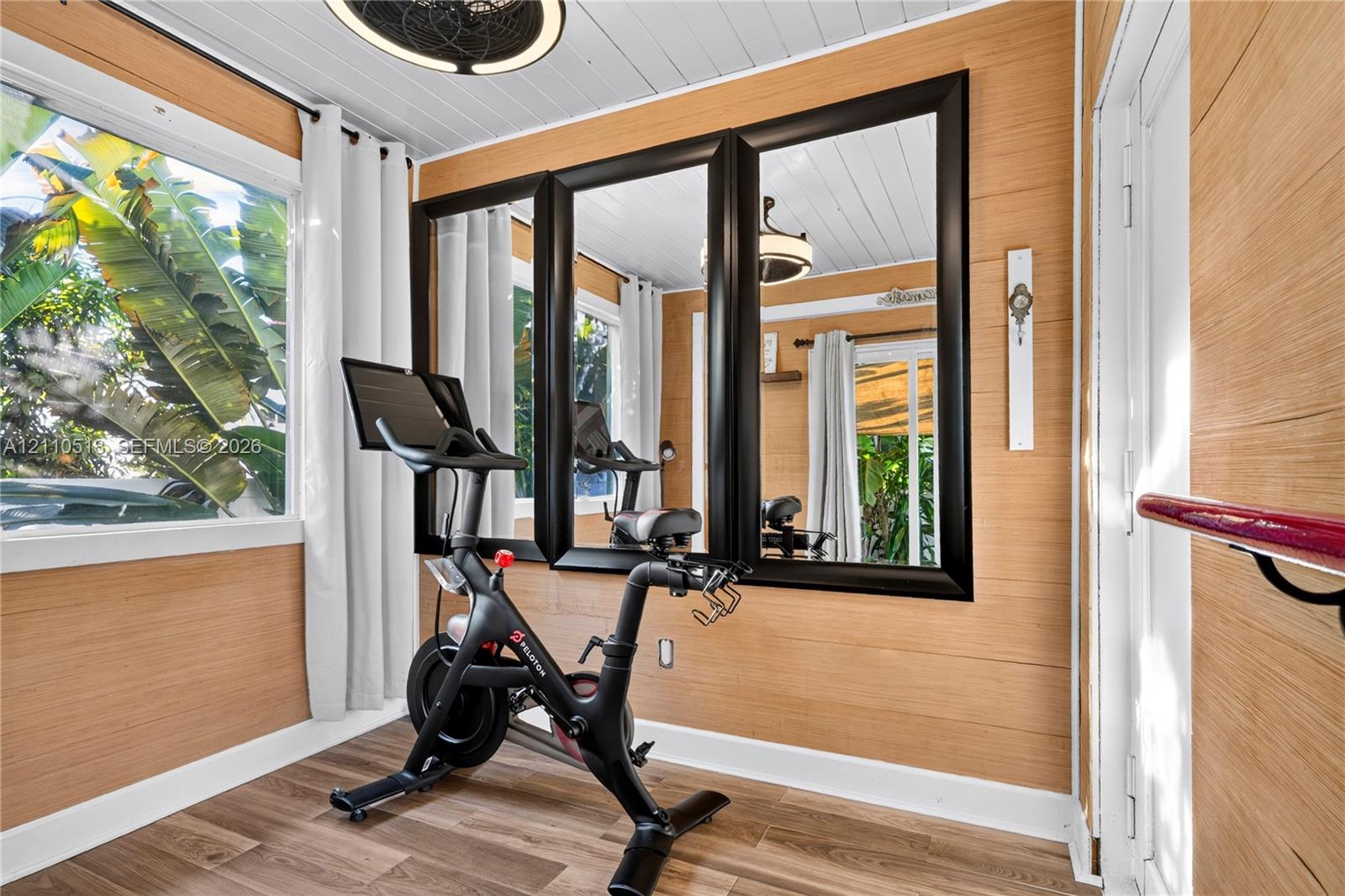 Horizontal wood-plank wall paneling, wood-finish flooring, white beadboard ceiling, and large, black-framed wall mirrors