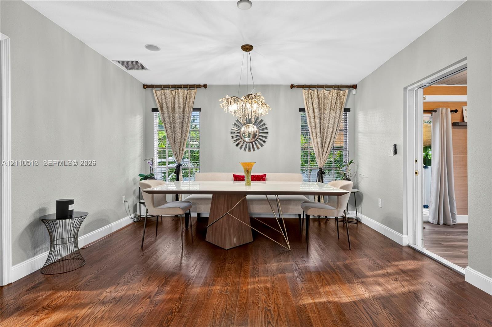 Dining space featuring wood-finish flooring, dual windows with decorative rods, and a suspended multi-light fixture