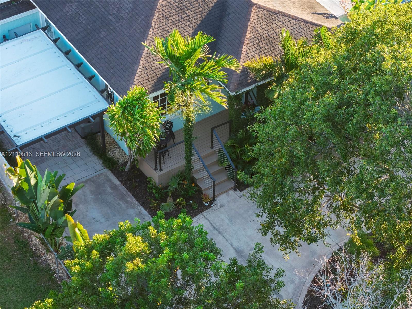 Exterior features include a concrete driveway, a covered parking structure, a wooden front deck with stairs, and mature landscaping Exterior features include a concrete driveway, a covered parking structure, a wooden front deck with stairs, and mature landscaping