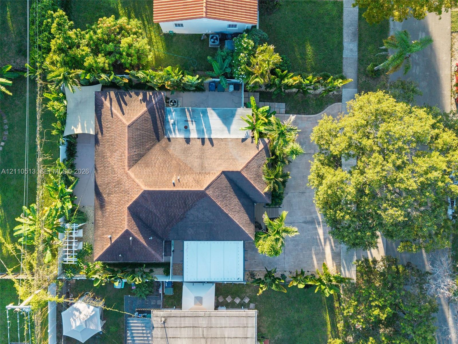 Aerial perspective featuring a multi-faceted shingle roof, concrete driveway, paved exterior patio, and mature landscaping Aerial perspective featuring a multi-faceted shingle roof, concrete driveway, paved exterior patio, and mature landscaping