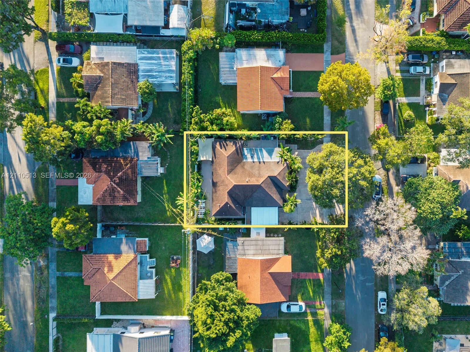 Aerial perspective of a property featuring a multi-pitched roof, concrete driveway, established trees, and perimeter landscaping within a residential neighborhood Aerial perspective of a property featuring a multi-pitched roof, concrete driveway, established trees, and perimeter landscaping within a residential neighborhood