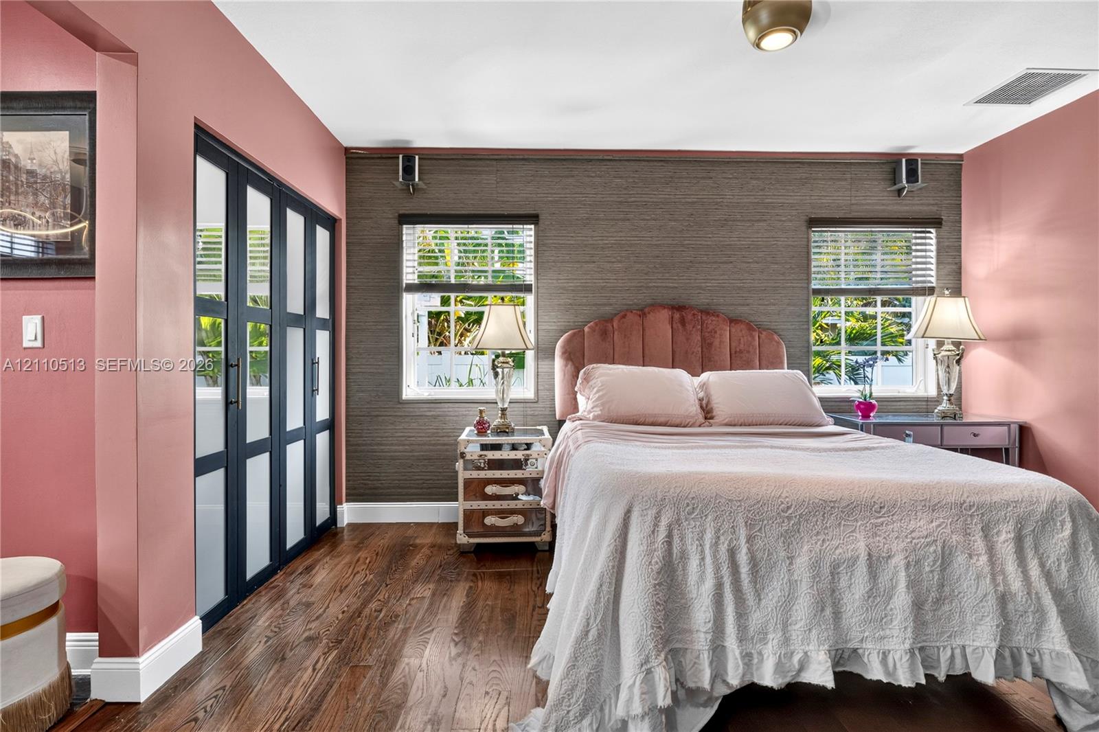 Wood-finish flooring, textured wall covering, double-hung windows, and floor-to-ceiling built-in closet with multi-pane glass doors