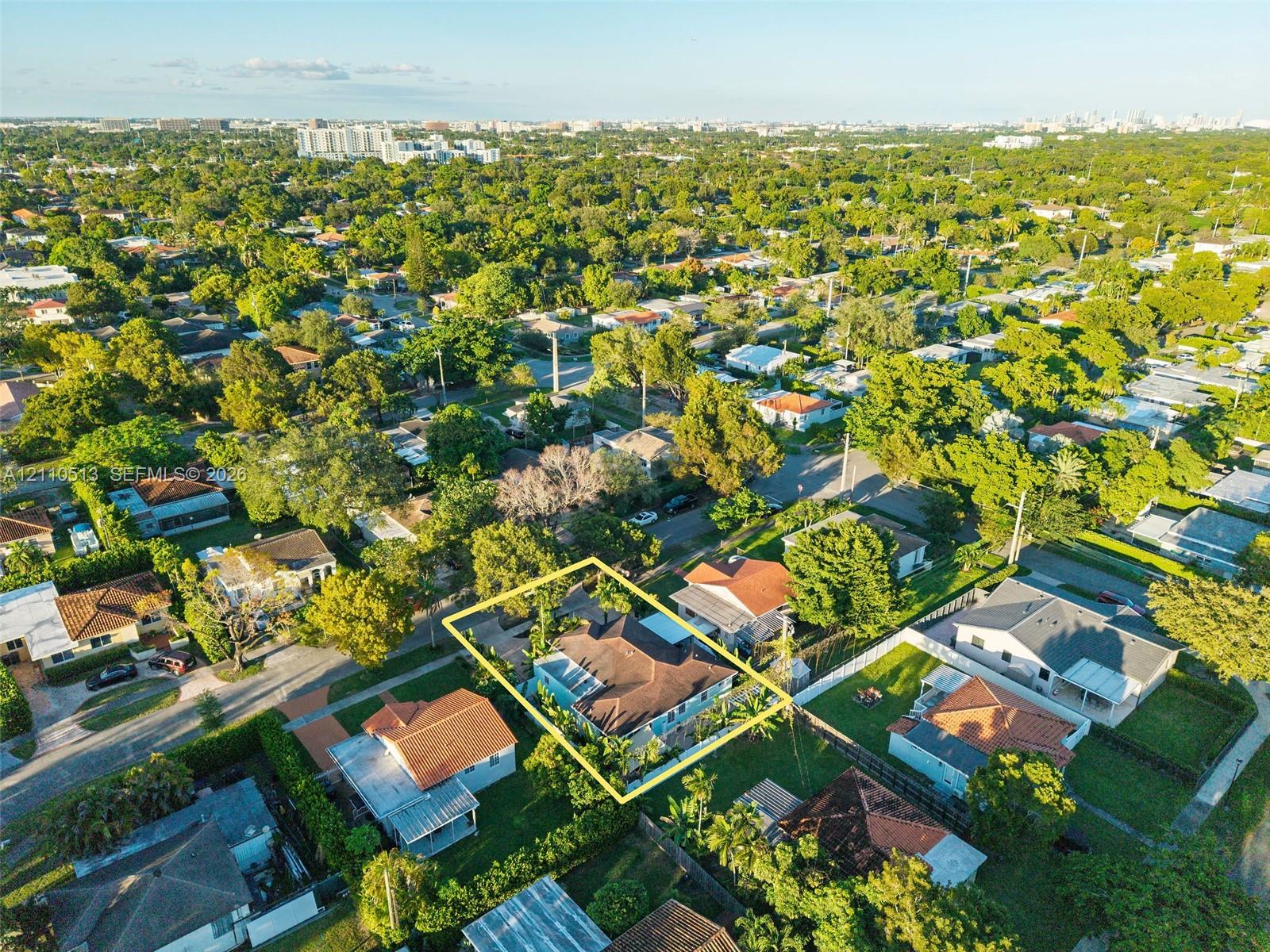 Aerial perspective of a residential property featuring a pitched roofline, paved driveway, enclosed backyard, and mature landscaping Aerial perspective of a residential property featuring a pitched roofline, paved driveway, enclosed backyard, and mature landscaping