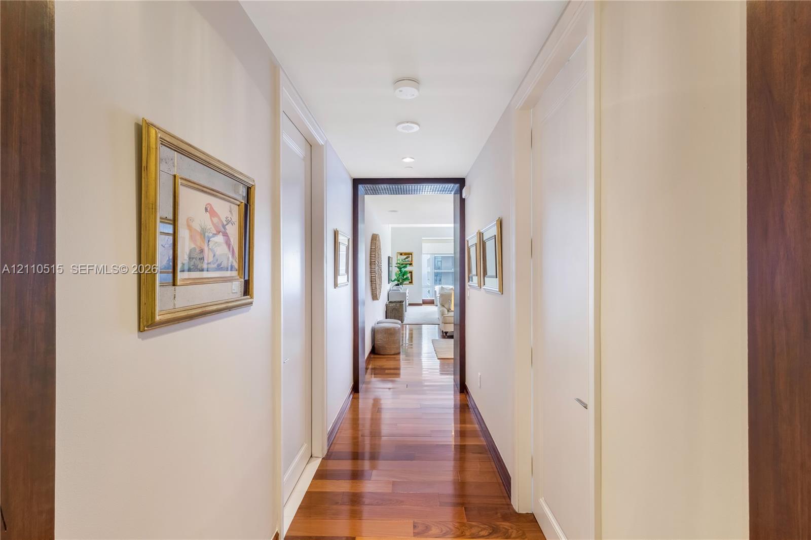 Hallway featuring wood-finish flooring, recessed ceiling lighting, and dark-toned door casings