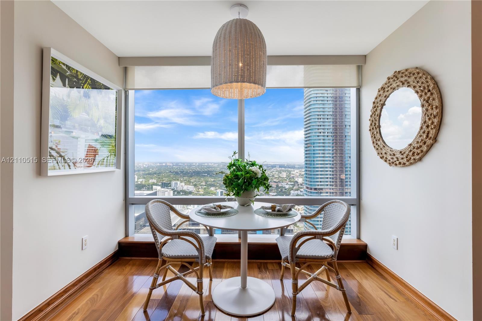 Floor-to-ceiling windows, wood-finish flooring, and a textured pendant light fixture