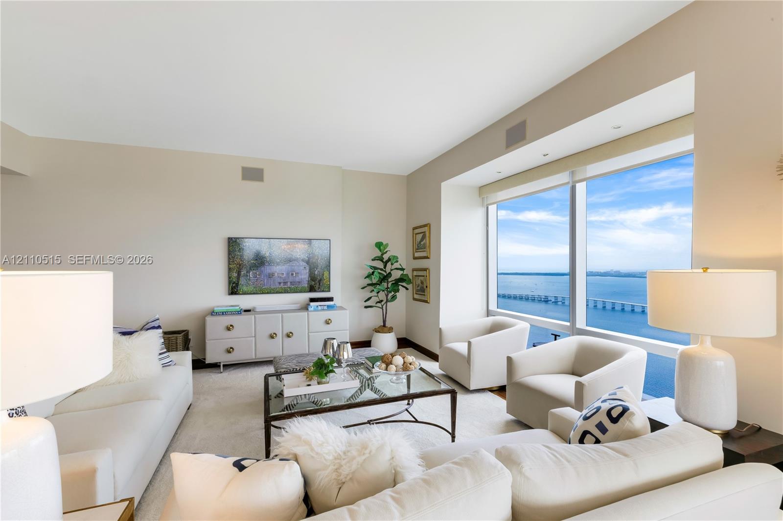 Living area featuring floor-to-ceiling windows, water and bridge backdrop, and neutral wall-to-wall carpeting