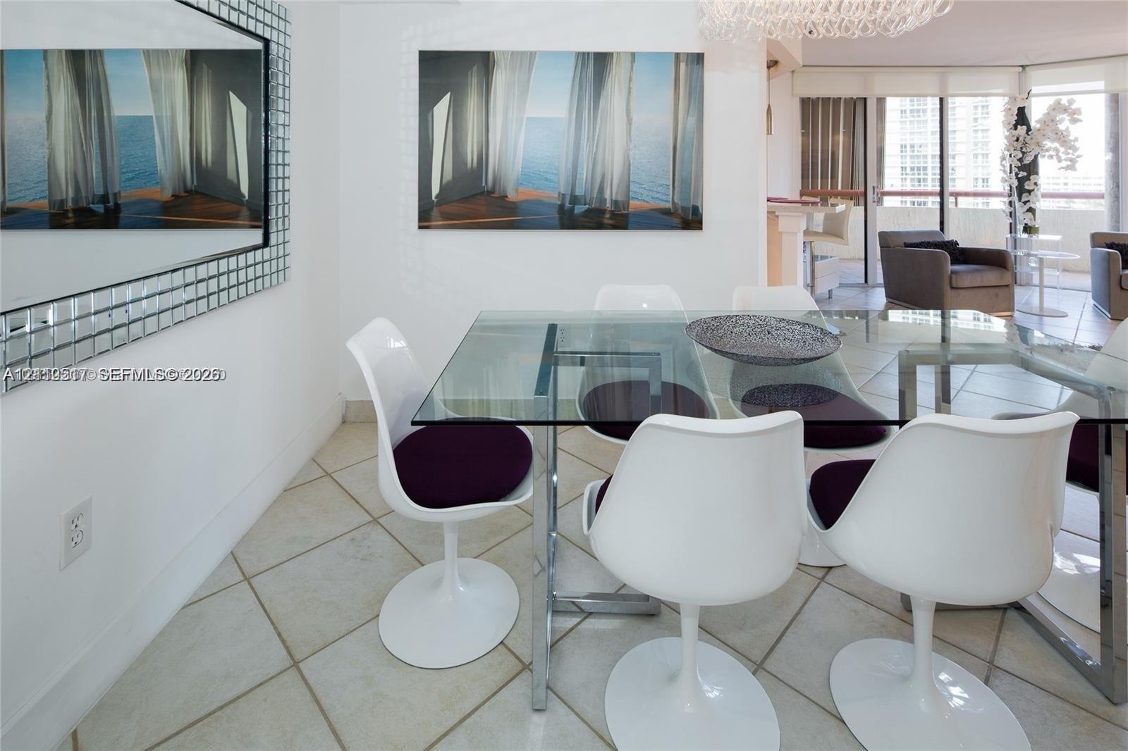 Large-format grid mirror with a metallic frame, expansive glass-paned sliding doors, polished tile flooring, and a contemporary crystal chandelier Large-format grid mirror with a metallic frame, expansive glass-paned sliding doors, polished tile flooring, and a contemporary crystal chandelier