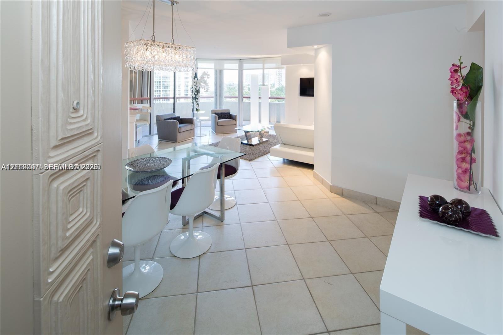 Large-format tile flooring, crystal-accented chandelier, and floor-to-ceiling glass paneling featuring balcony access Large-format tile flooring, crystal-accented chandelier, and floor-to-ceiling glass paneling featuring balcony access
