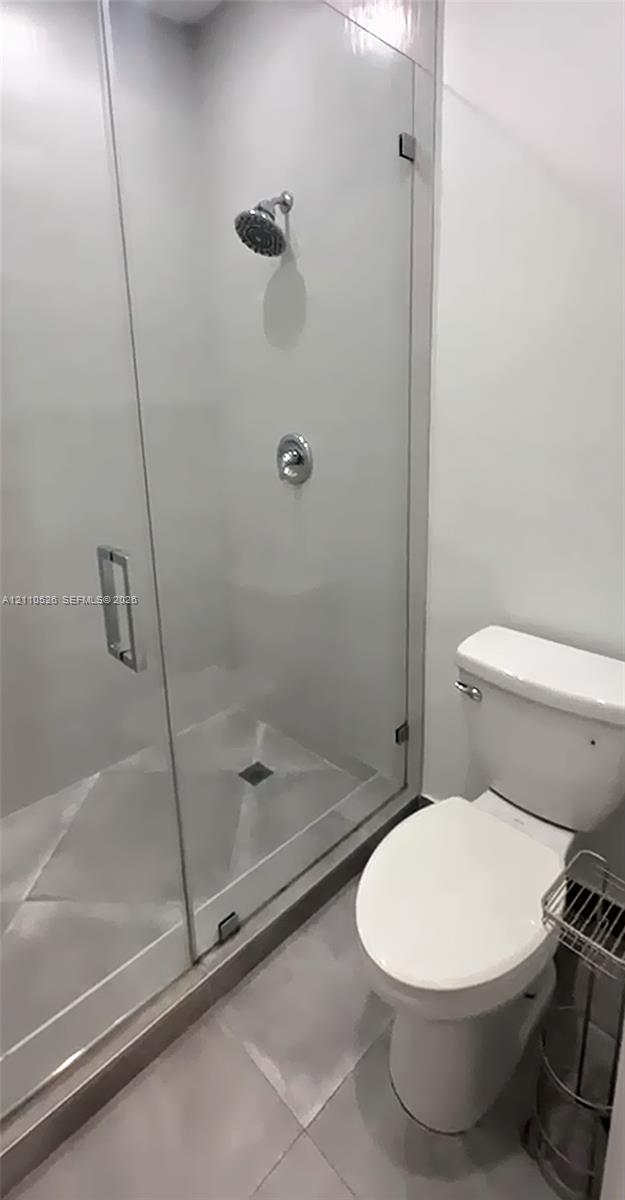 Glass-enclosed shower with polished chrome fixtures and tile flooring