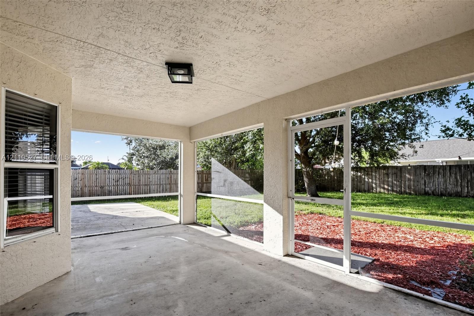 Screened-in patio with concrete flooring, stucco exterior walls, flush-mount lighting, and direct access to a fenced backyard