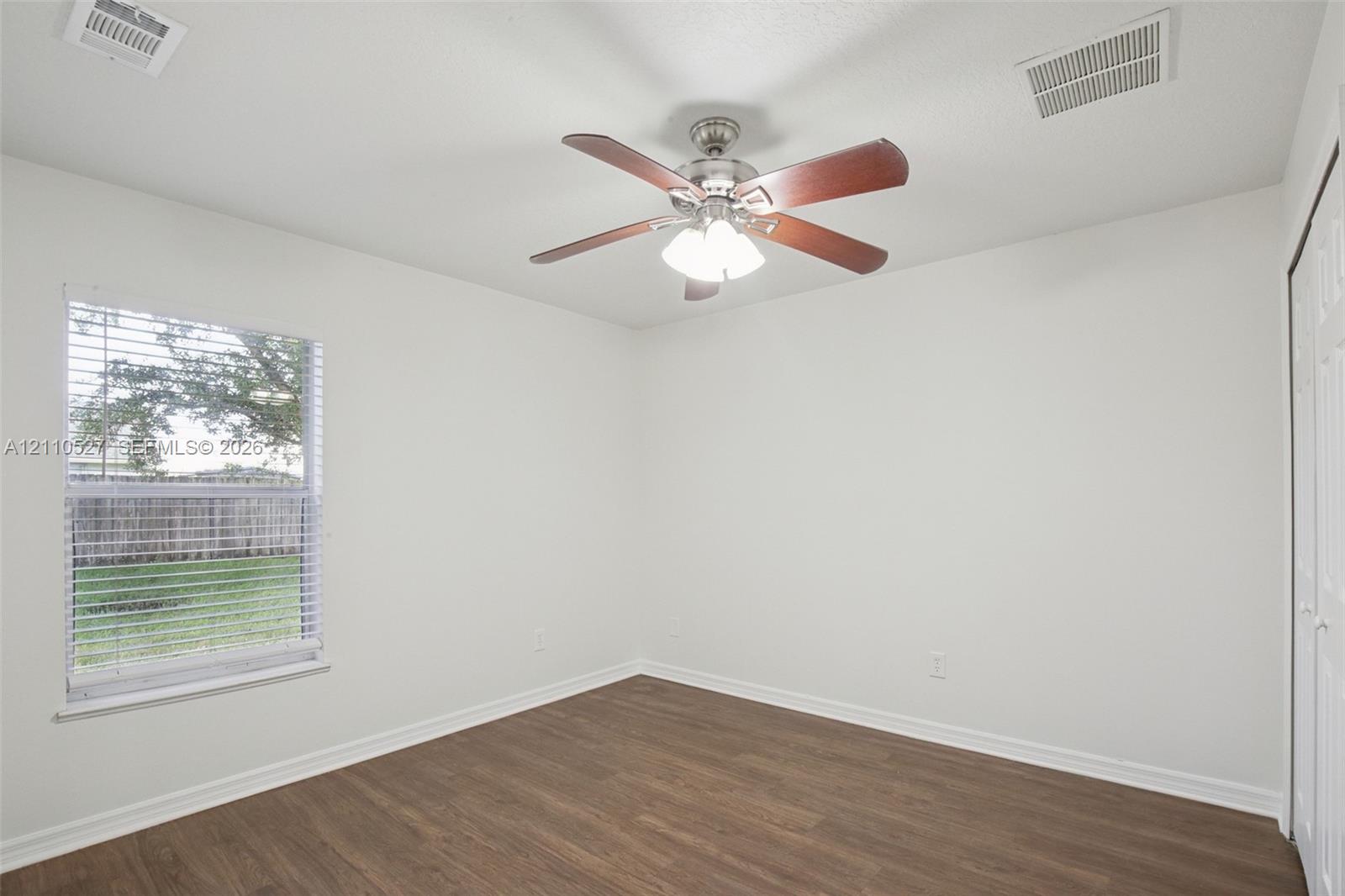 Interior space featuring wood-finish flooring, a ceiling fan with integrated lighting, and a single window with horizontal blinds