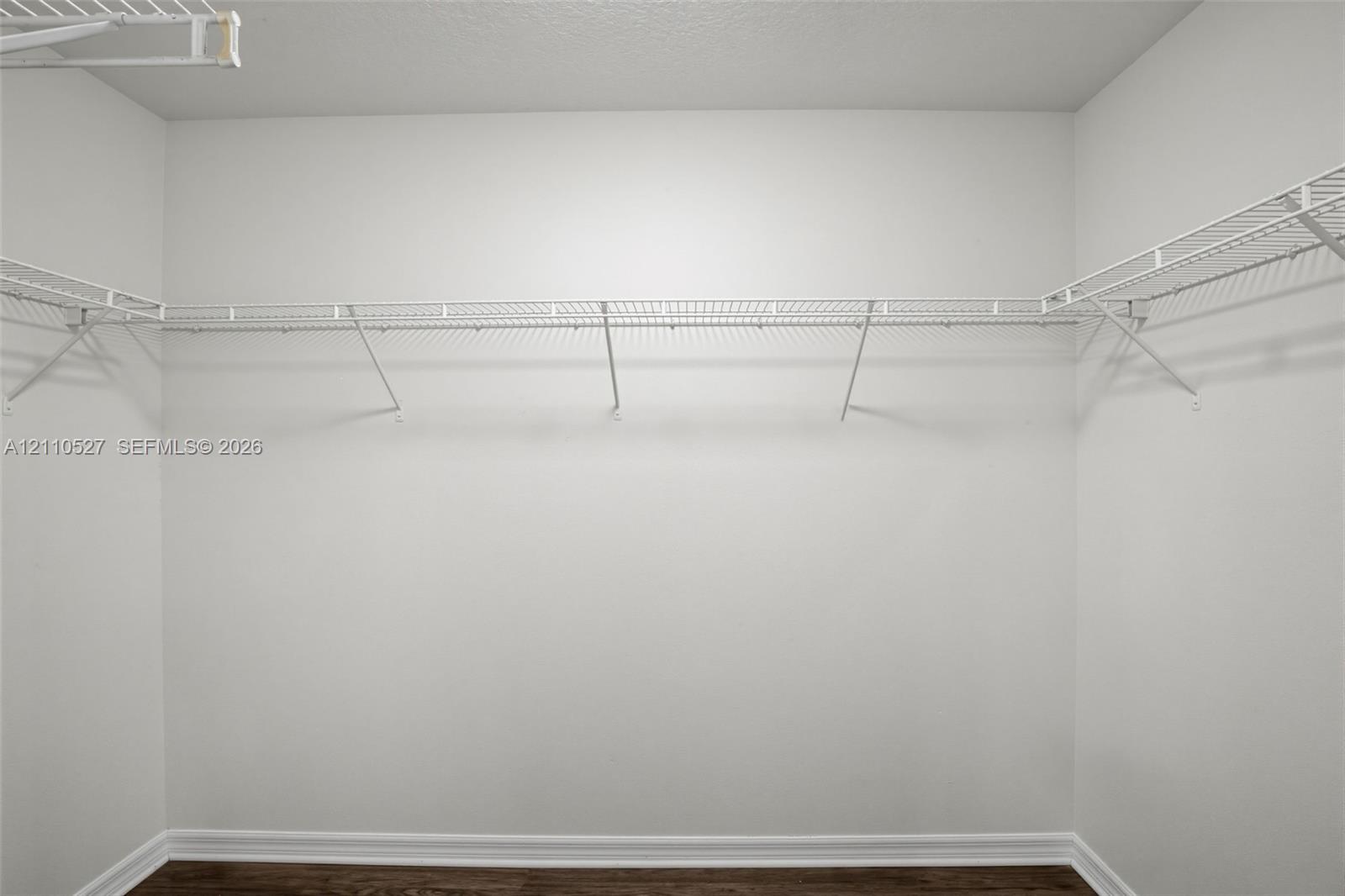 Walk-in closet featuring white wire shelving and wood-finish flooring