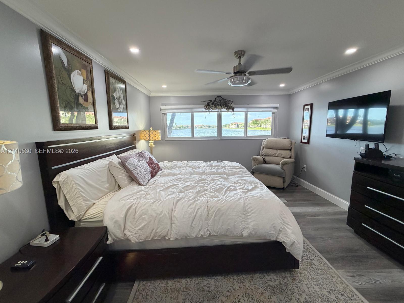 Wood-finish flooring, recessed lighting, crown molding, ceiling fan, and waterfront window exposure