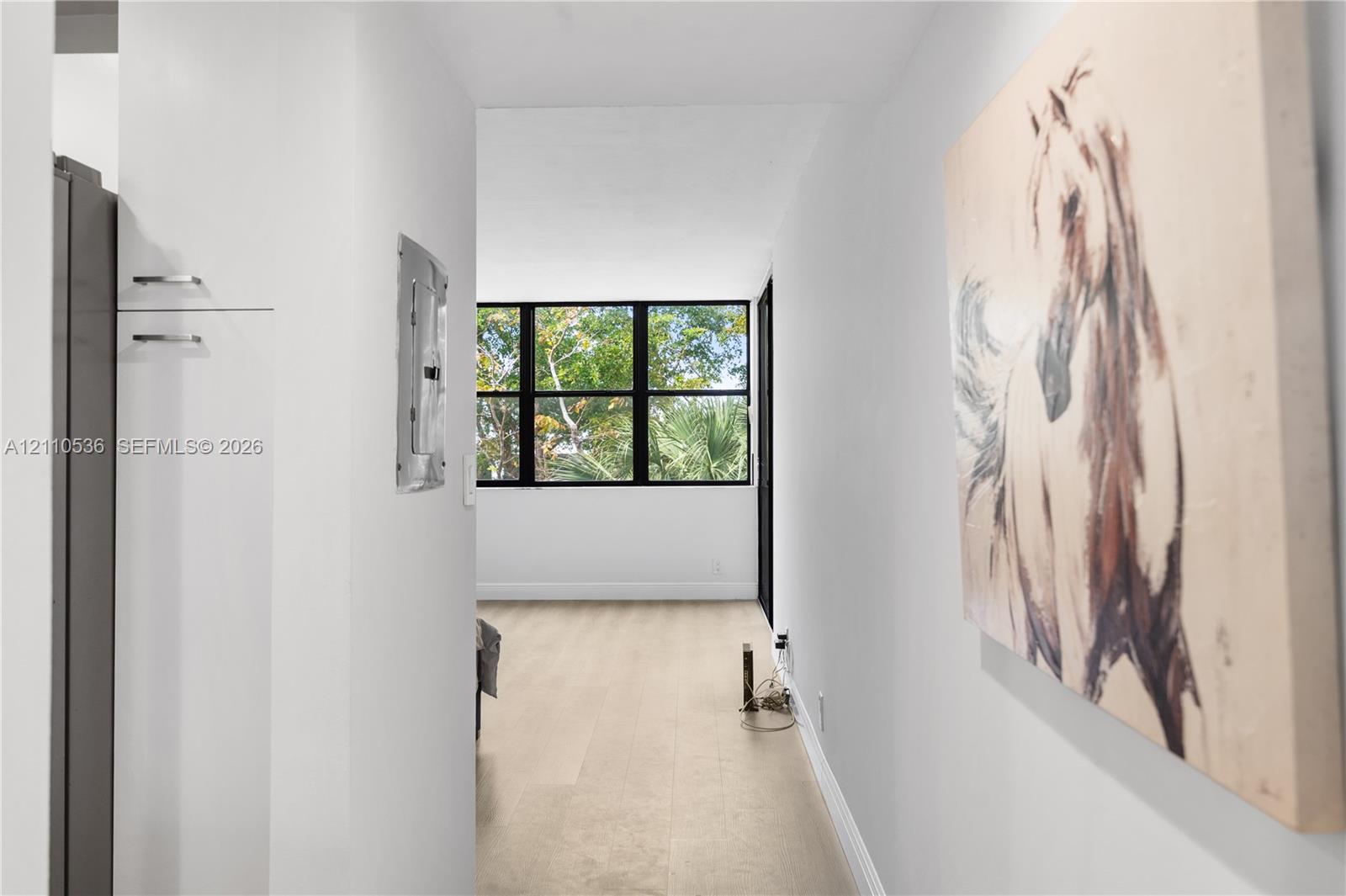 Interior hallway featuring neutral walls, light-toned flooring, and black-framed windows Interior hallway featuring neutral walls, light-toned flooring, and black-framed windows