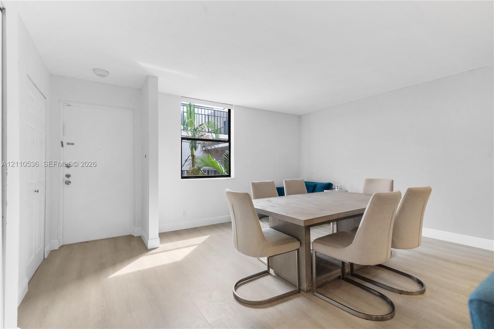 Light-filled interior featuring wood-finish flooring, white walls, and a single-pane window Light-filled interior featuring wood-finish flooring, white walls, and a single-pane window
