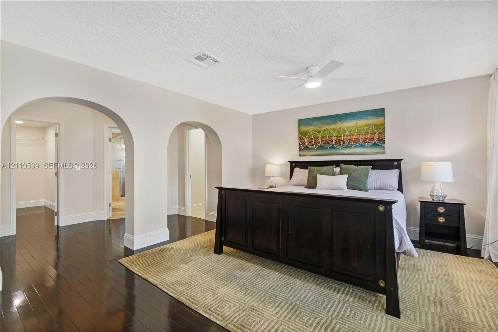 Interior space featuring dark wood-finish flooring, dual arched entryways, and a ceiling-mounted light fixture with an integrated fan