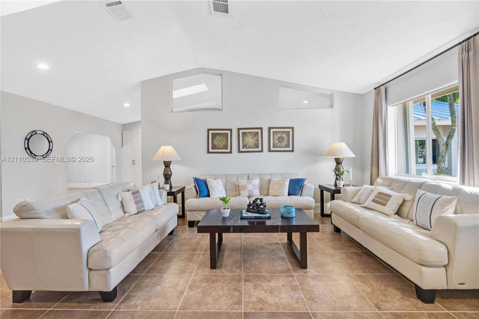 Living room featuring vaulted ceilings, oversized tile flooring, recessed lighting, and clerestory windows