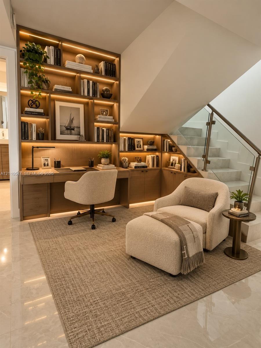 Custom built-in cabinetry featuring integrated LED shelf lighting and a coordinated workspace desk, complemented by a staircase with structural glass railing and stone-finish steps