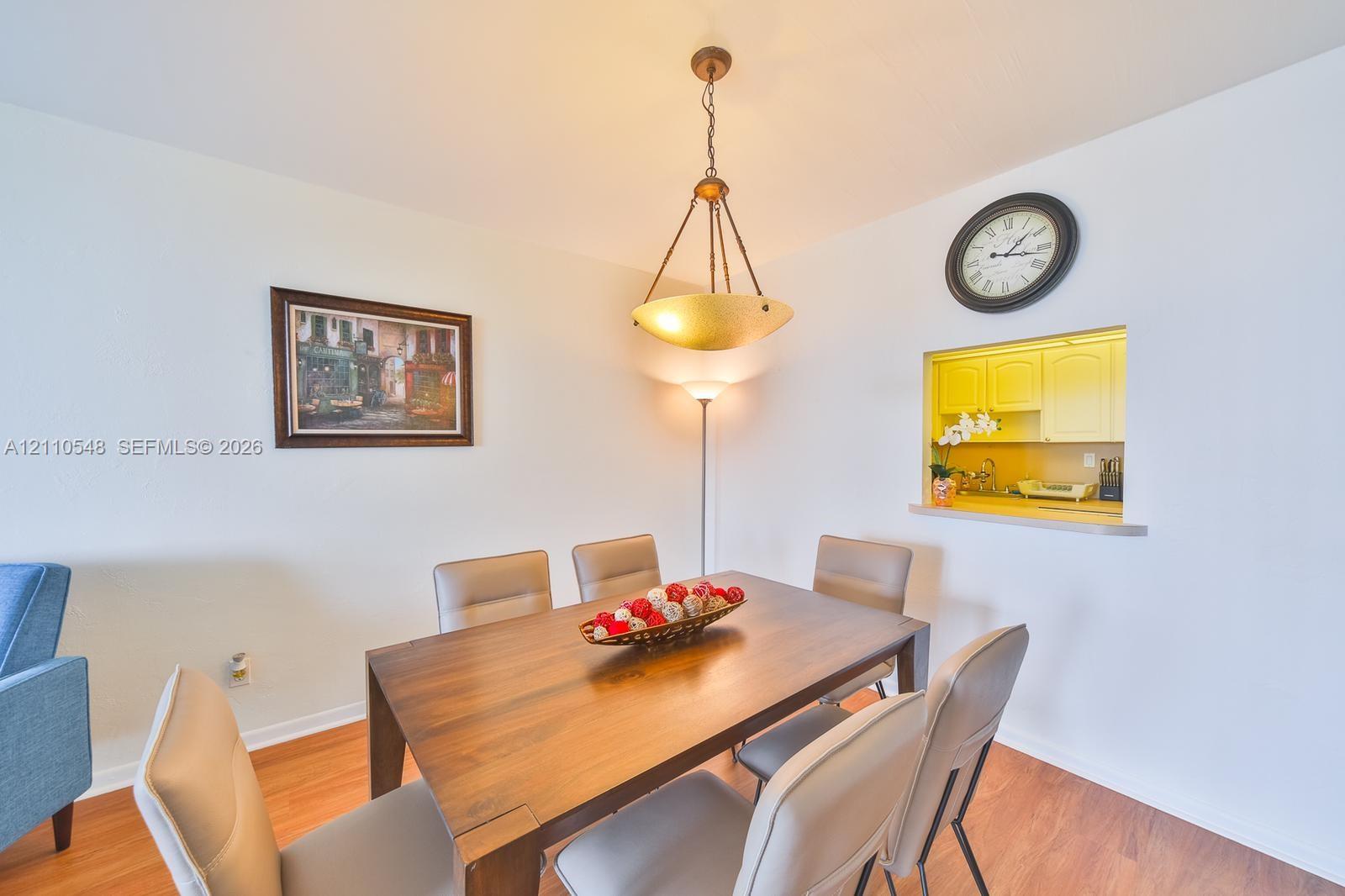 Wood-finish flooring, metal inverted pendant light fixture, and interior pass-through window opening to cabinetry