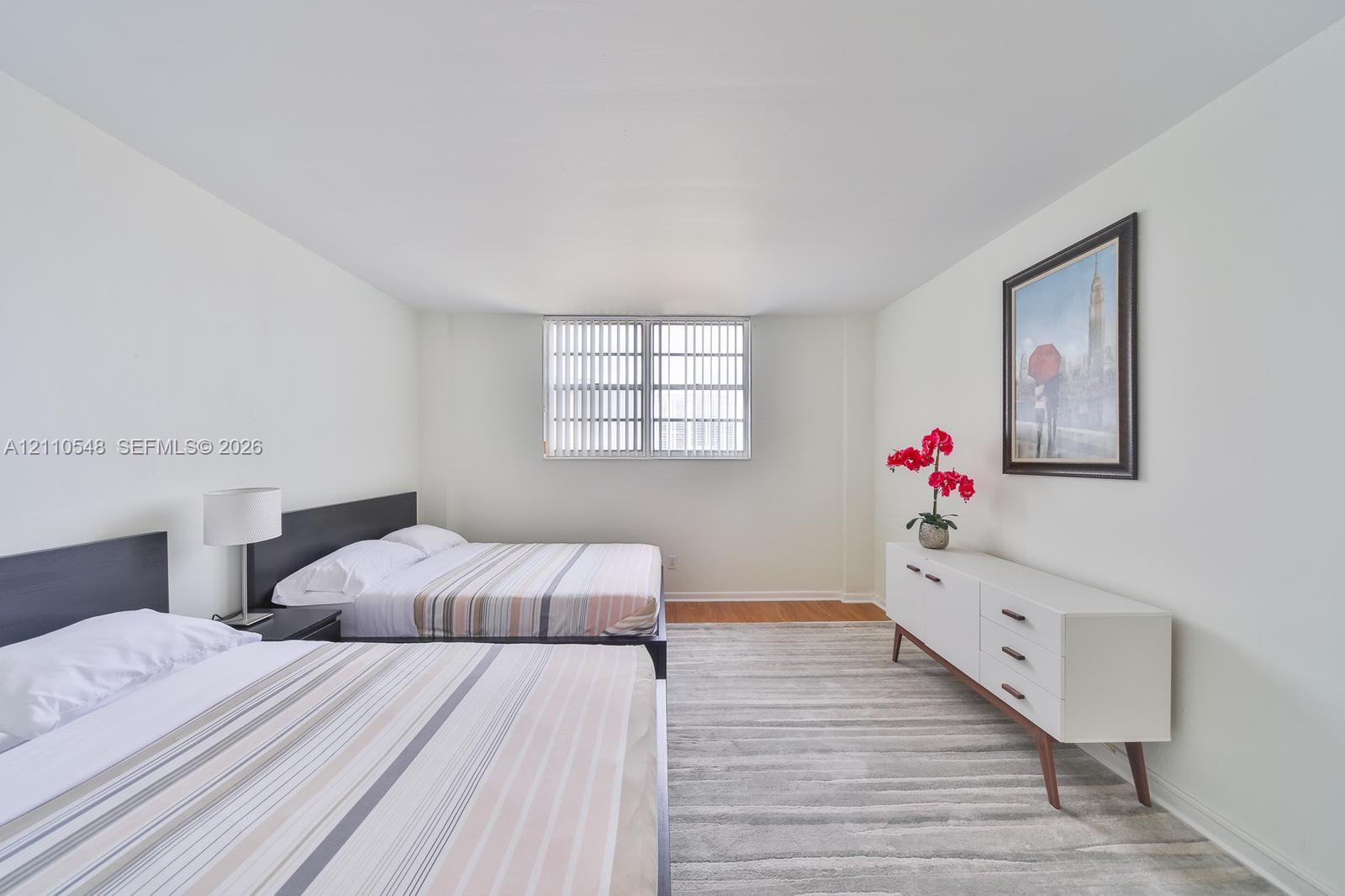 Spacious room featuring neutral paint, wood-finish flooring, and a large window with vertical blinds