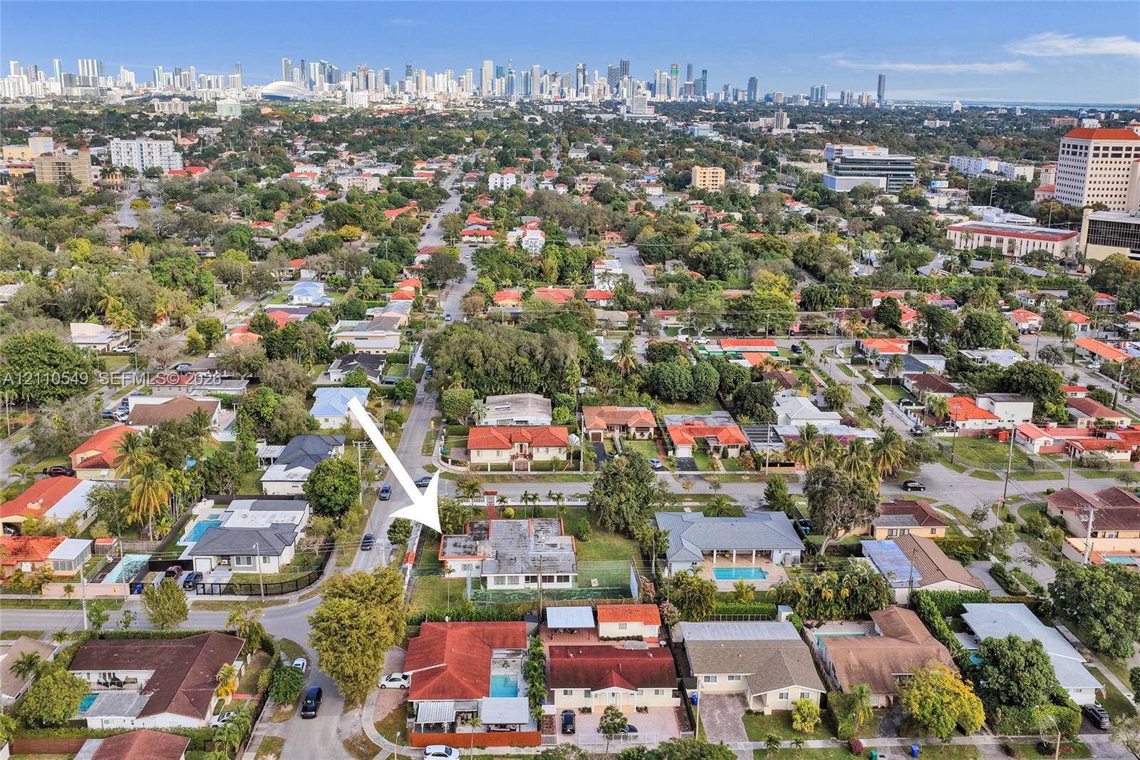 Aerial perspective of residential property featuring a flat-roof structure, expansive lot, and proximity to the urban skyline