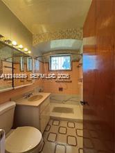 Bathroom featuring a vanity with an integrated basin, wall-mounted mirror cabinetry, and decorative tiled tub surround with an overhead shower fixture