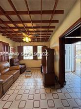 Grid-patterned ceiling feature with exposed wooden beams, tile flooring, and integrated ceiling fan