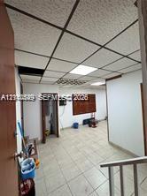 Interior space featuring grid-pattern acoustic drop ceiling tiles, integrated recessed lighting, and light-toned ceramic tile flooring