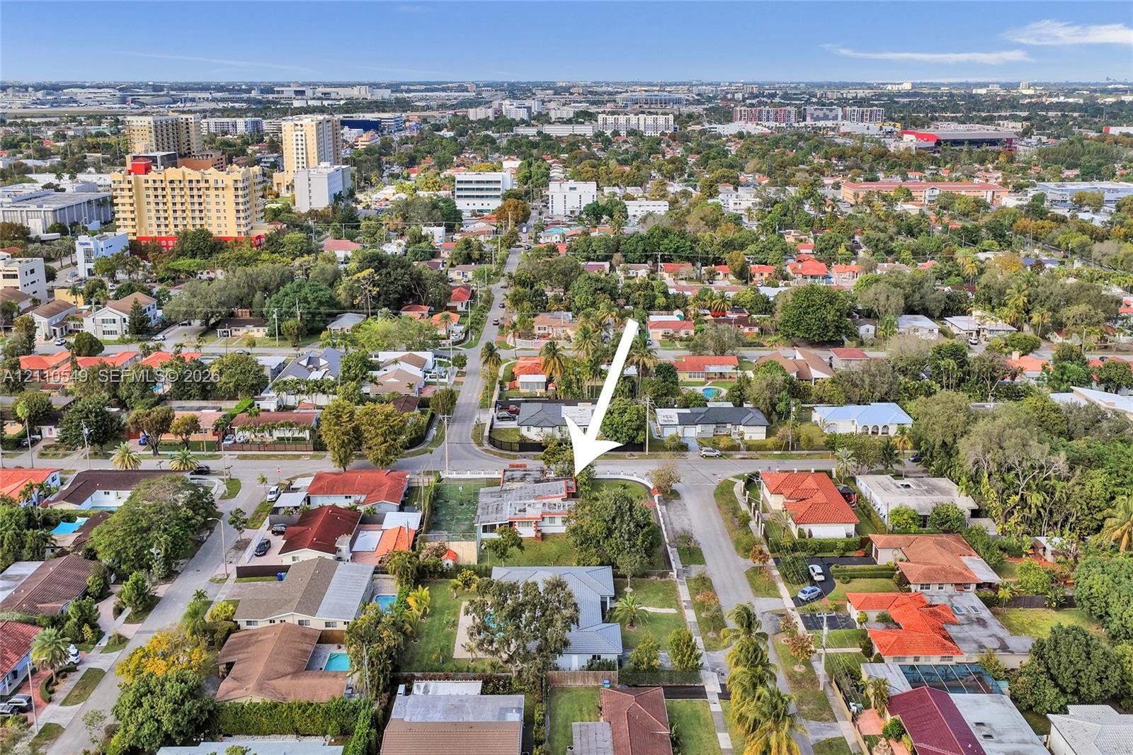 Aerial perspective of a corner lot property featuring a rectangular-shaped structure, perimeter fencing, and mature trees