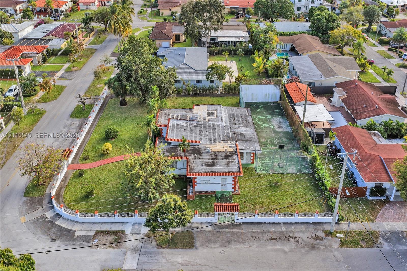 Corner lot featuring a perimeter wall with decorative accents, an expansive yard, and a dedicated hard-surface sports court