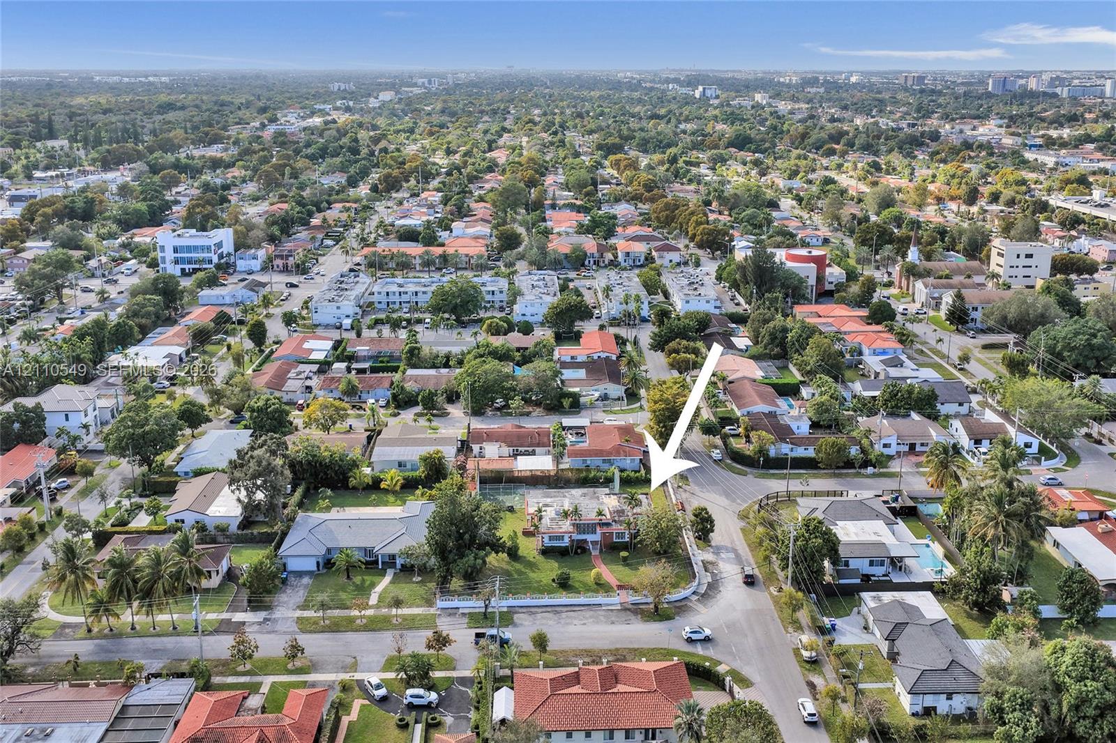 Aerial perspective featuring a corner lot with mature landscaping, fenced perimeter, and street access