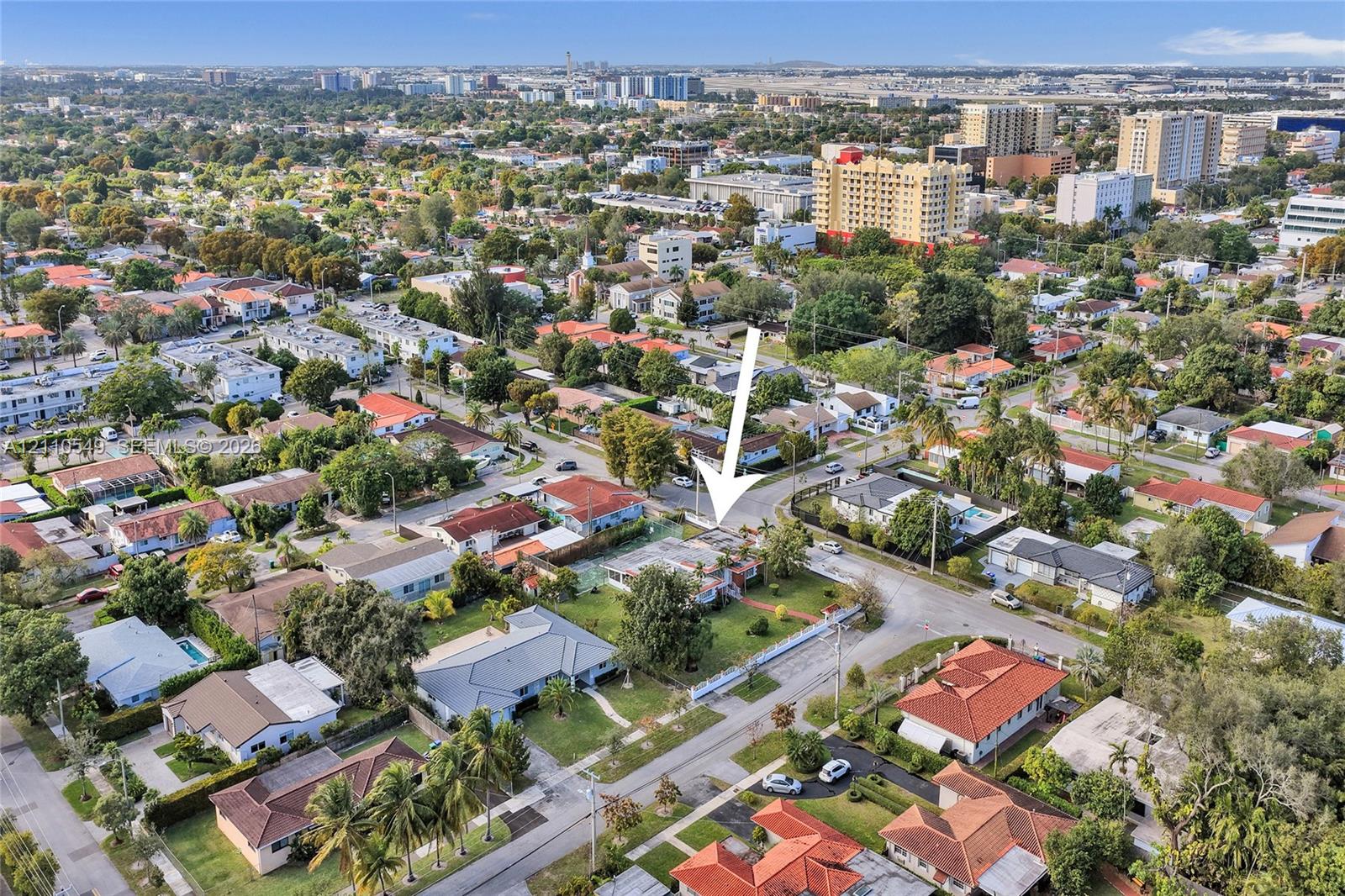 Aerial perspective of a residential property featuring a corner lot, mature landscaping, fenced perimeter, and driveway