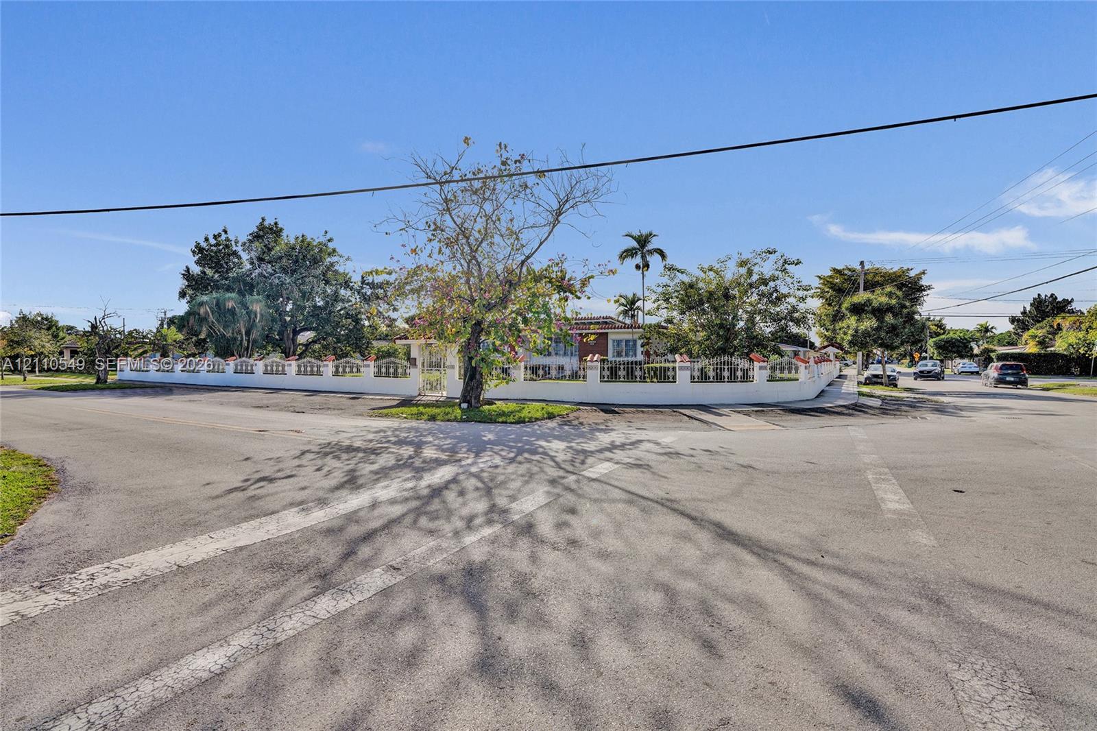 Corner lot property featuring a perimeter masonry wall with decorative accents, mature landscaping, and established trees