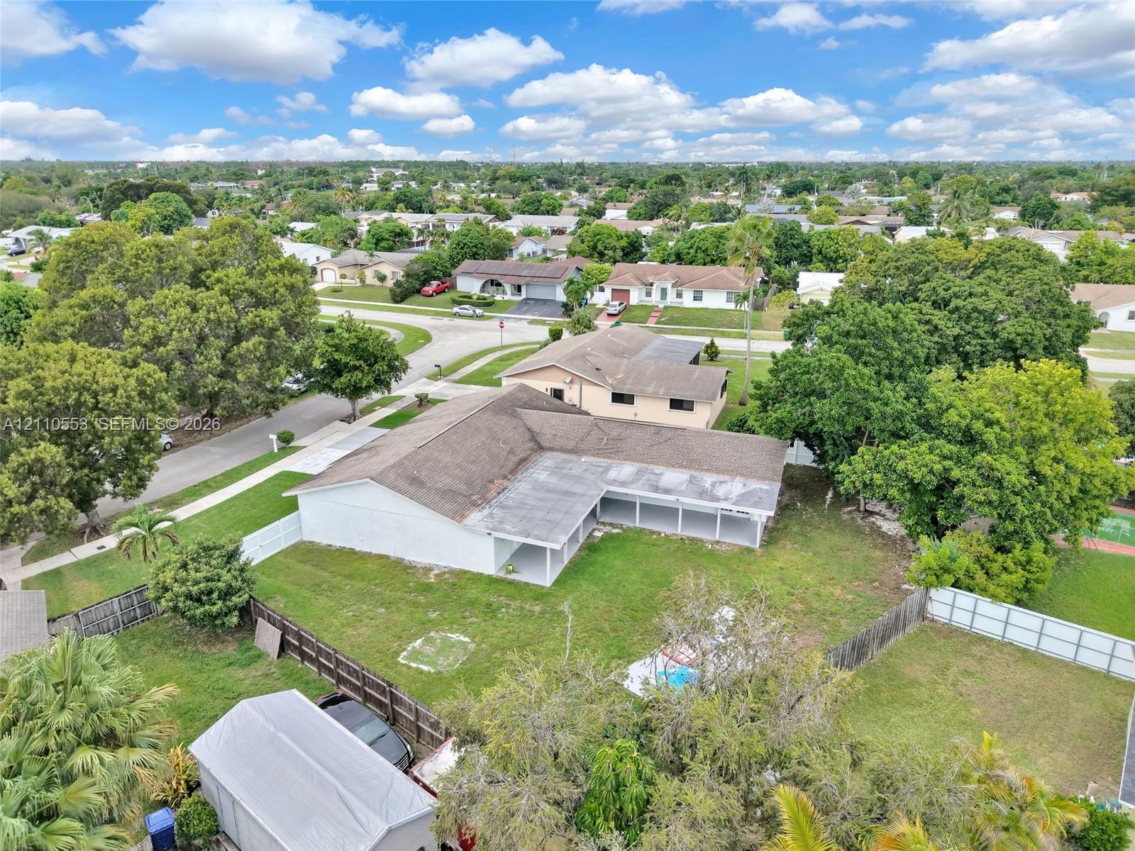 Single-story residence featuring a shingle roof, rear-facing covered patio, fenced backyard, and a detached storage structure