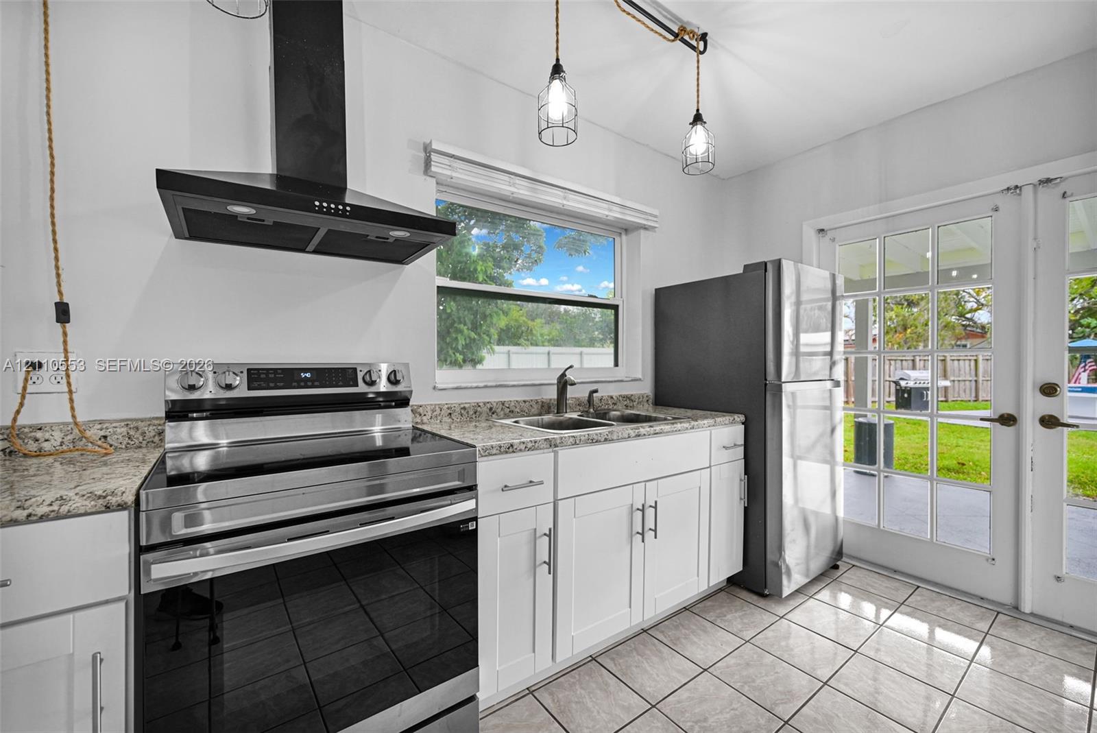 Kitchen featuring white cabinetry, stone-surface countertops, a stainless steel range, a black chimney-style range hood, and tile flooring