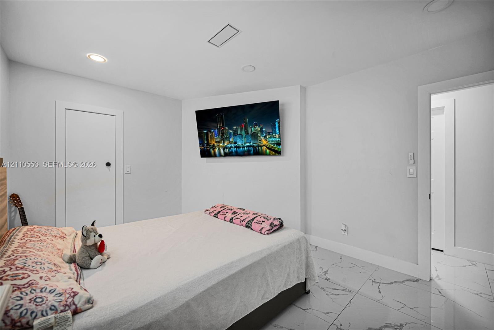 Neutral-toned interior featuring large-format stone-patterned tile flooring and recessed lighting