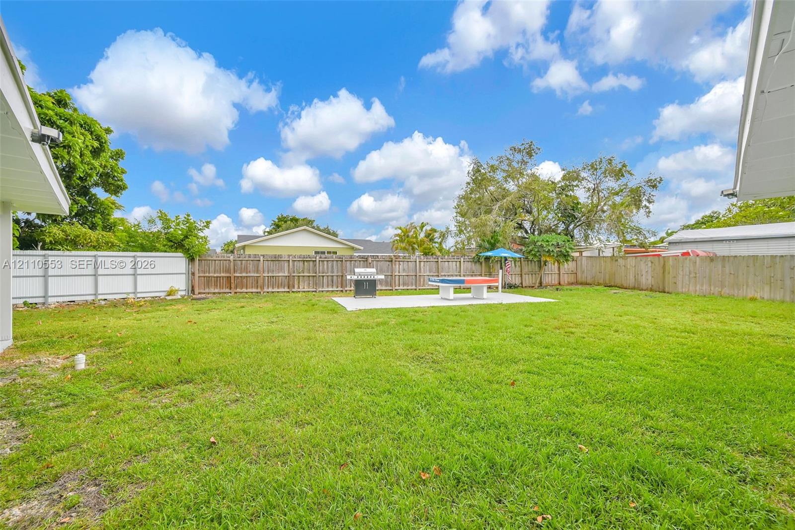 Expansive backyard featuring a level lawn, concrete patio, and wood privacy fencing