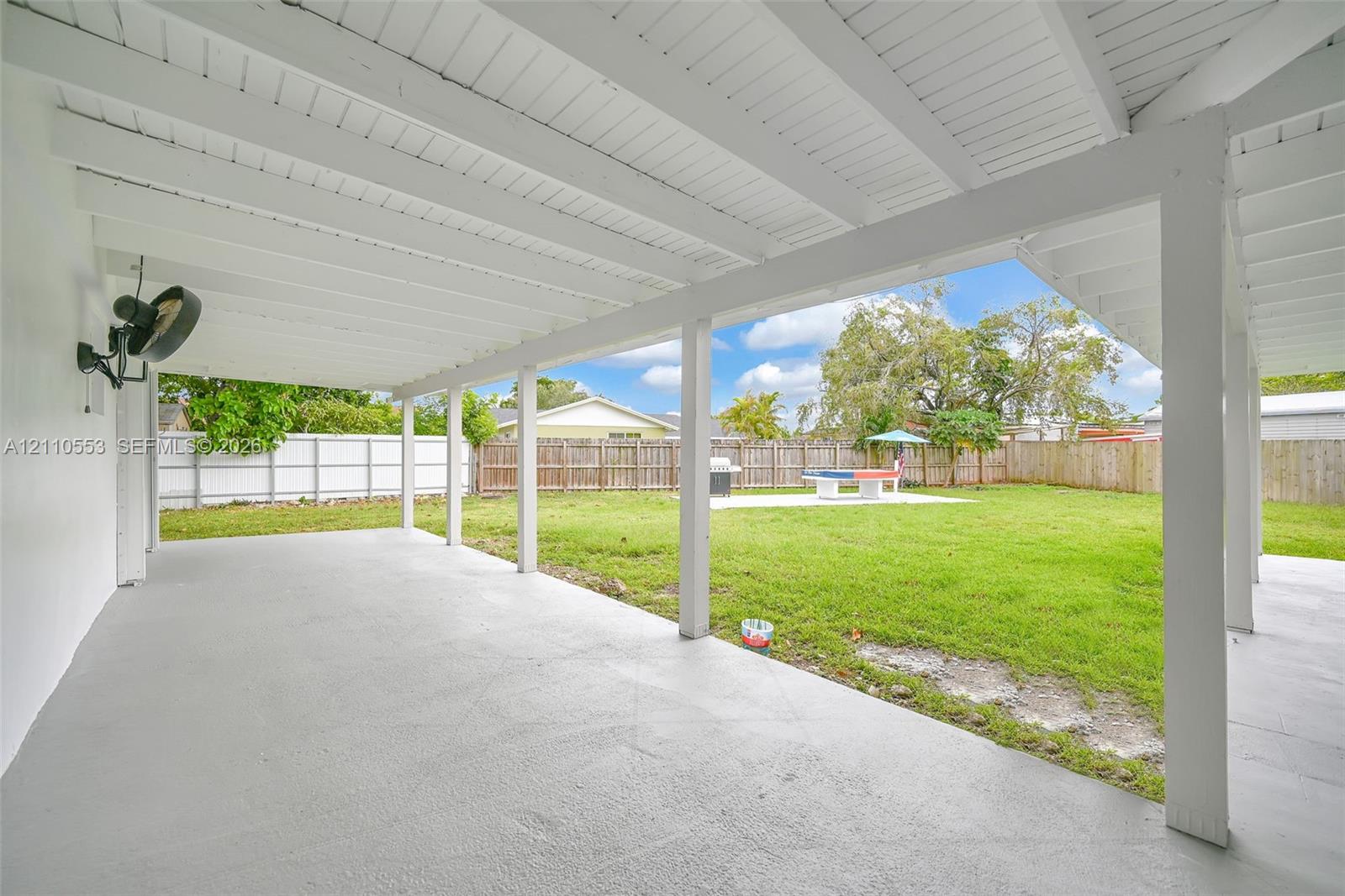 Covered patio featuring an exposed-beam ceiling, concrete flooring, and a fenced backyard