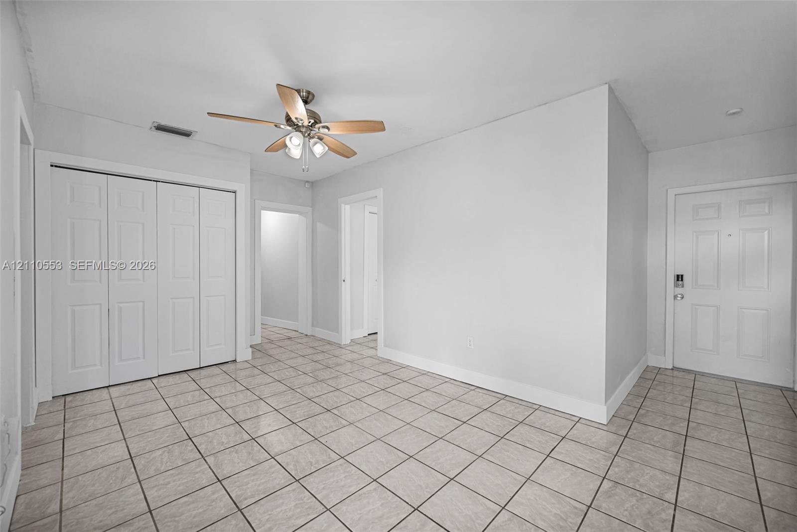 Interior space featuring neutral wall paint, grid-pattern tile flooring, a multi-panel door, built-in closet with multi-panel doors, and a ceiling-mounted light fixture with a fan