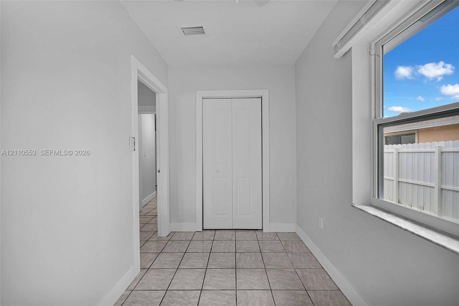 Interior space featuring ceramic tile flooring, a dual-panel closet door, and a single-pane window with a stone-finish sill