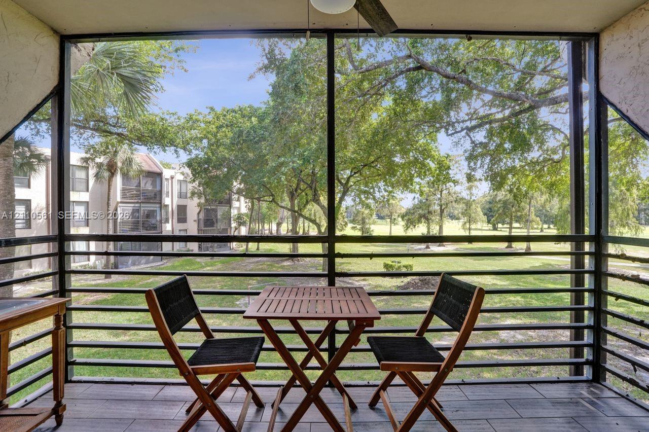 Screened-in balcony featuring wood-finish tile flooring, ceiling fan, and metal railings
