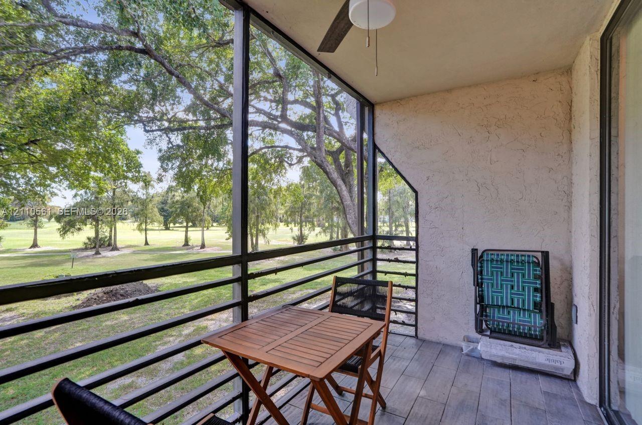 Screened-in balcony featuring wood-finish flooring, metal railing, and a ceiling-mounted fan