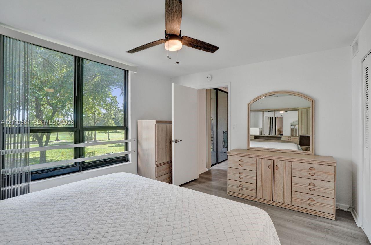 Floor-to-ceiling windows, wood-finish flooring, and a ceiling fan with integrated lighting