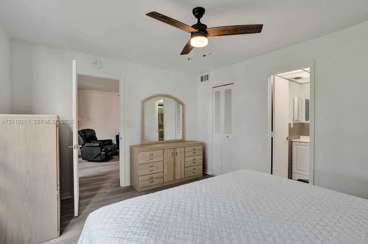 Ceiling fan with integrated lighting, wood-finish flooring, and white louvered-panel closet doors