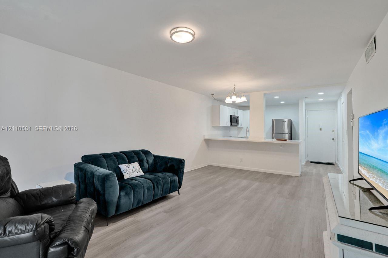 Open-concept area featuring wood-finish flooring, a breakfast bar, recessed lighting, and white cabinetry