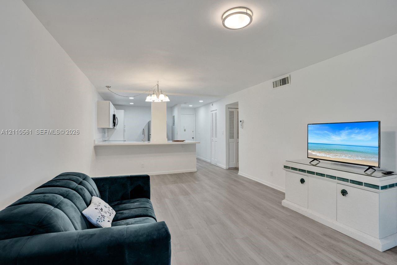 Open-concept floor plan featuring wood-finish flooring, a breakfast bar, recessed lighting, and a decorative chandelier
