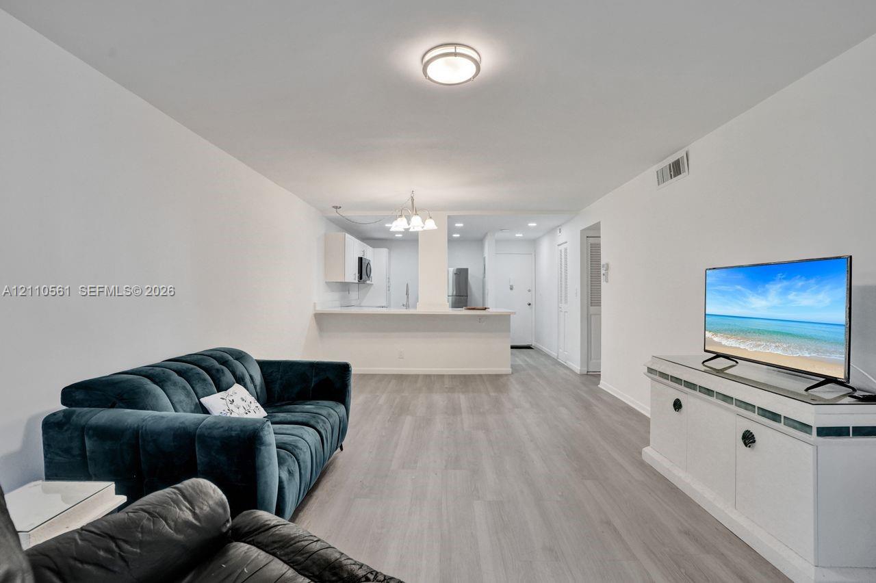 Open floor plan featuring wood-finish flooring, recessed ceiling lighting, and a kitchen peninsula with a breakfast bar