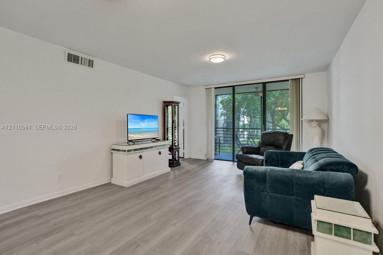 Living area featuring neutral wall paint, wood-finish flooring, a central flush-mount ceiling light, and large sliding glass doors providing outdoor access