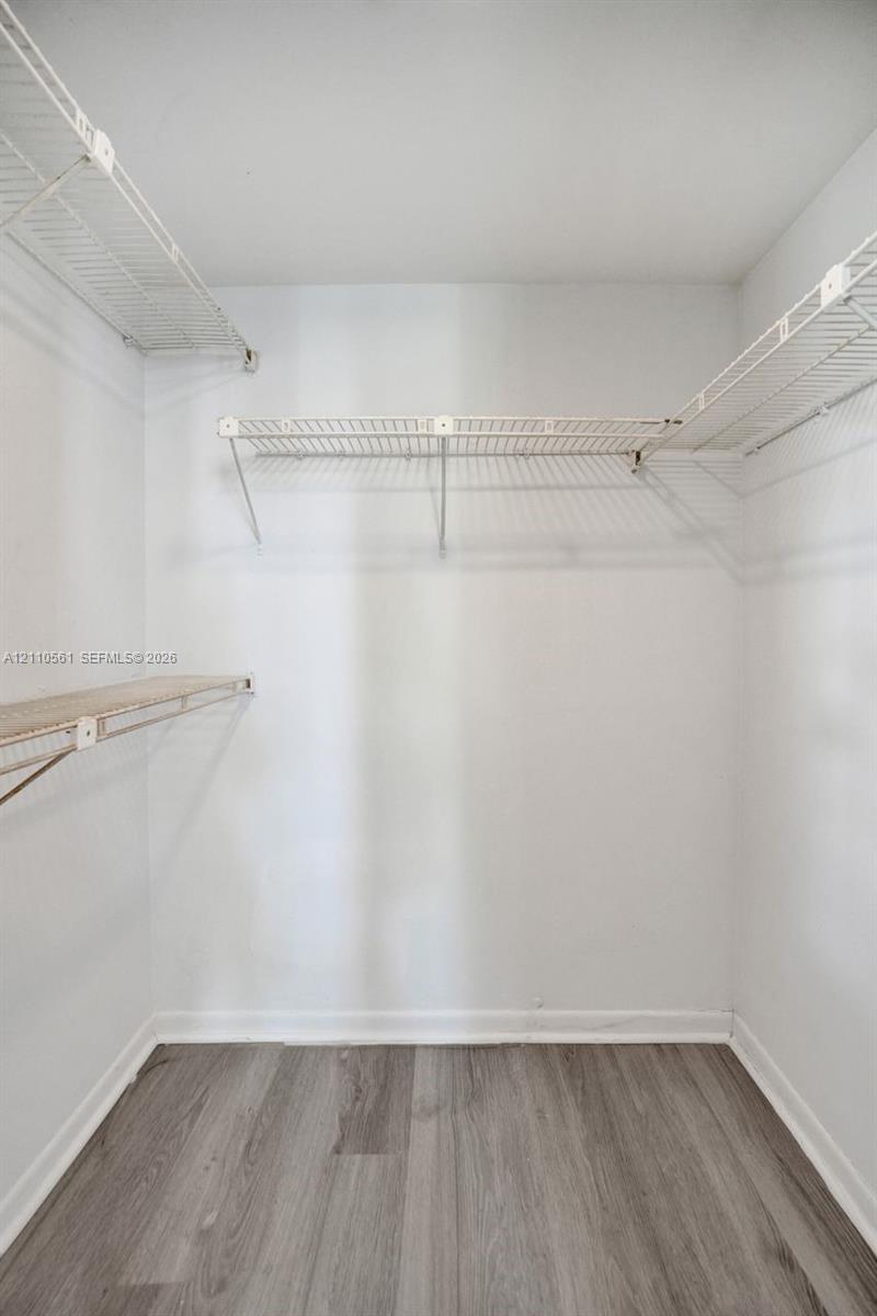 Storage space featuring multi-level white wire shelving and wood-finish flooring